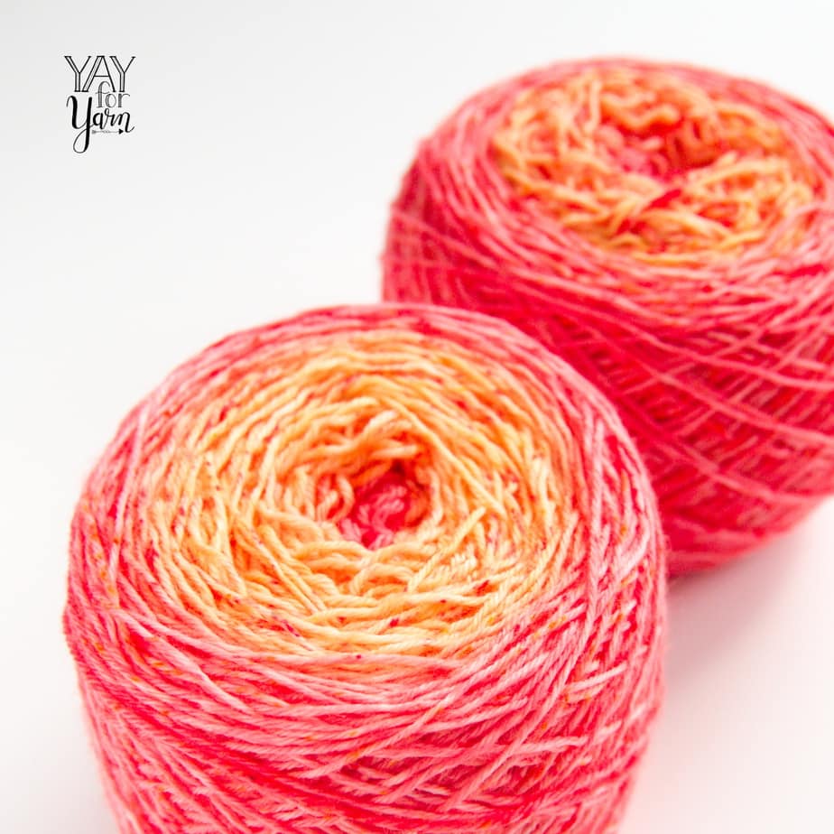 two gradient cakes of hand dyed yarn - coral and orange with red speckles