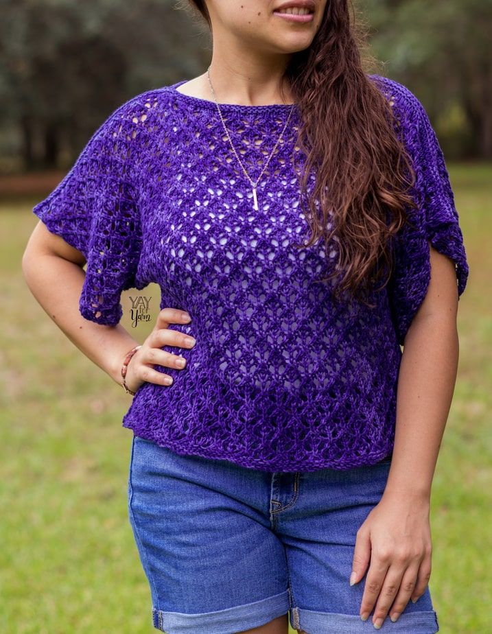 girl standing with hand on hip, wearing blue violet knitted lace tee with jean shorts