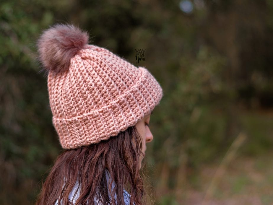 girl wearing pink crochet ski hat with brown fur pom pom