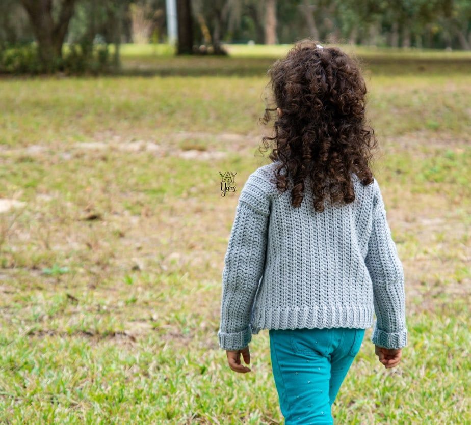 little girl in grey crochet cardigan walking
