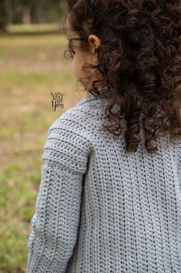 close-up of a little girl in gray crochet cardigan