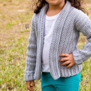 child wearing grey crocheted cardigan with white shirt and teal green pants