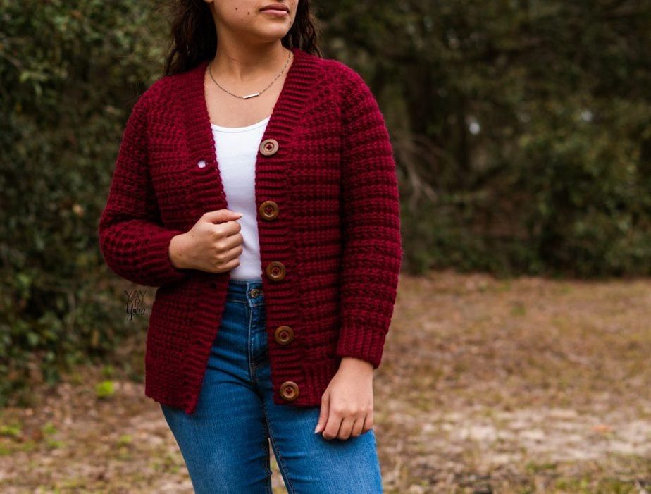 woman wearing crimson crochet cardigan outdoors, with white top and jeans