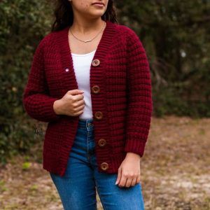 woman wearing crimson crochet cardigan outdoors, with white top and jeans