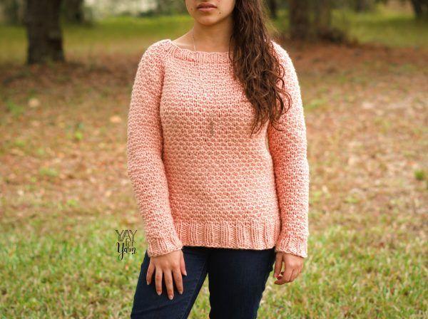 front view of a girl outdoors wearing a knitted pullover in pink and black jeans