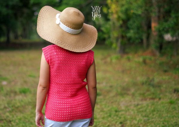 rear view of a girl outdoors wearing a brown beach hat with white crochet bow and a crochet tee in red