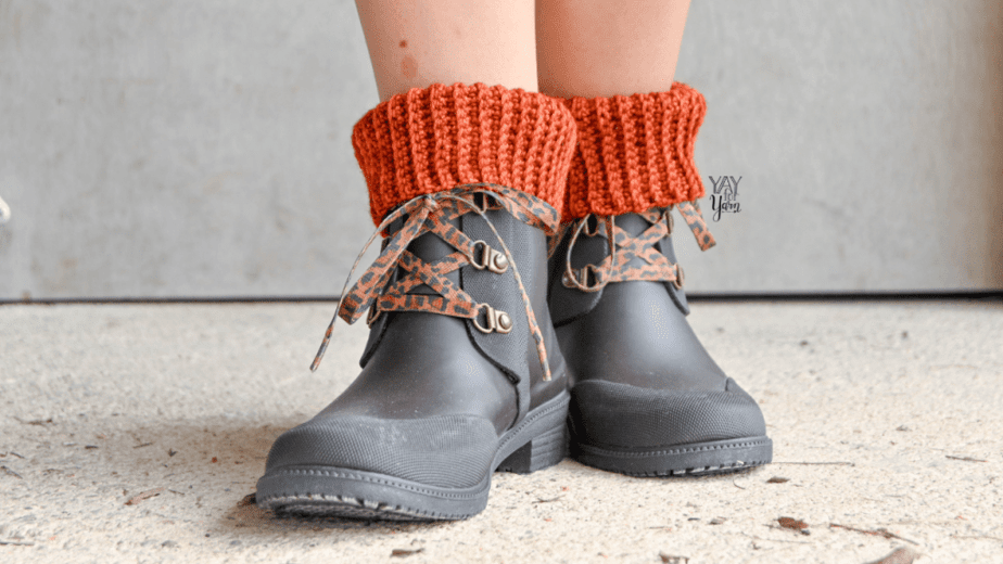 feet wearing dark brown lace up boots with dark orange ribbed crochet boot cuffs